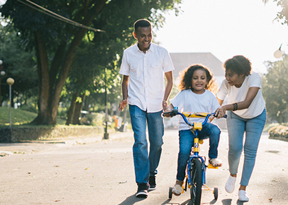 Couple teaching child to ride bike