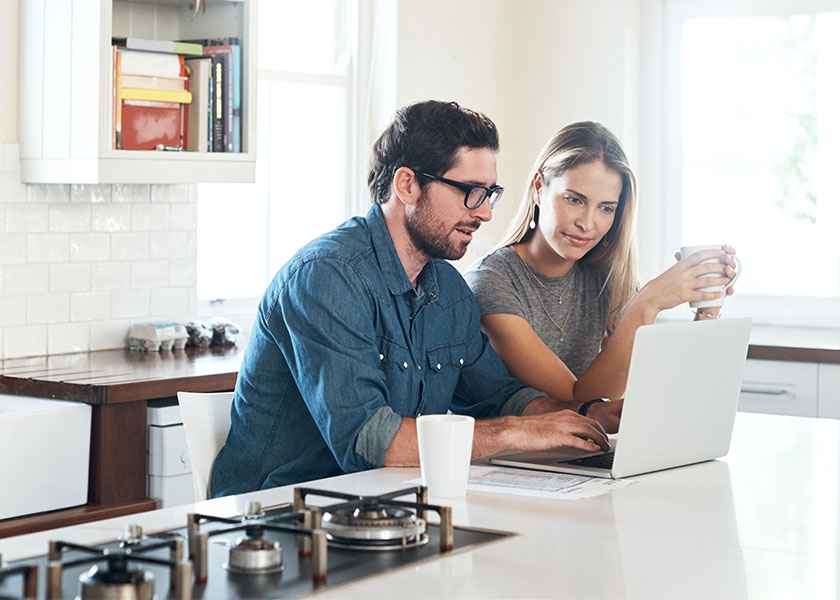 Shot of a young couple using a laptop together at home to create a will.