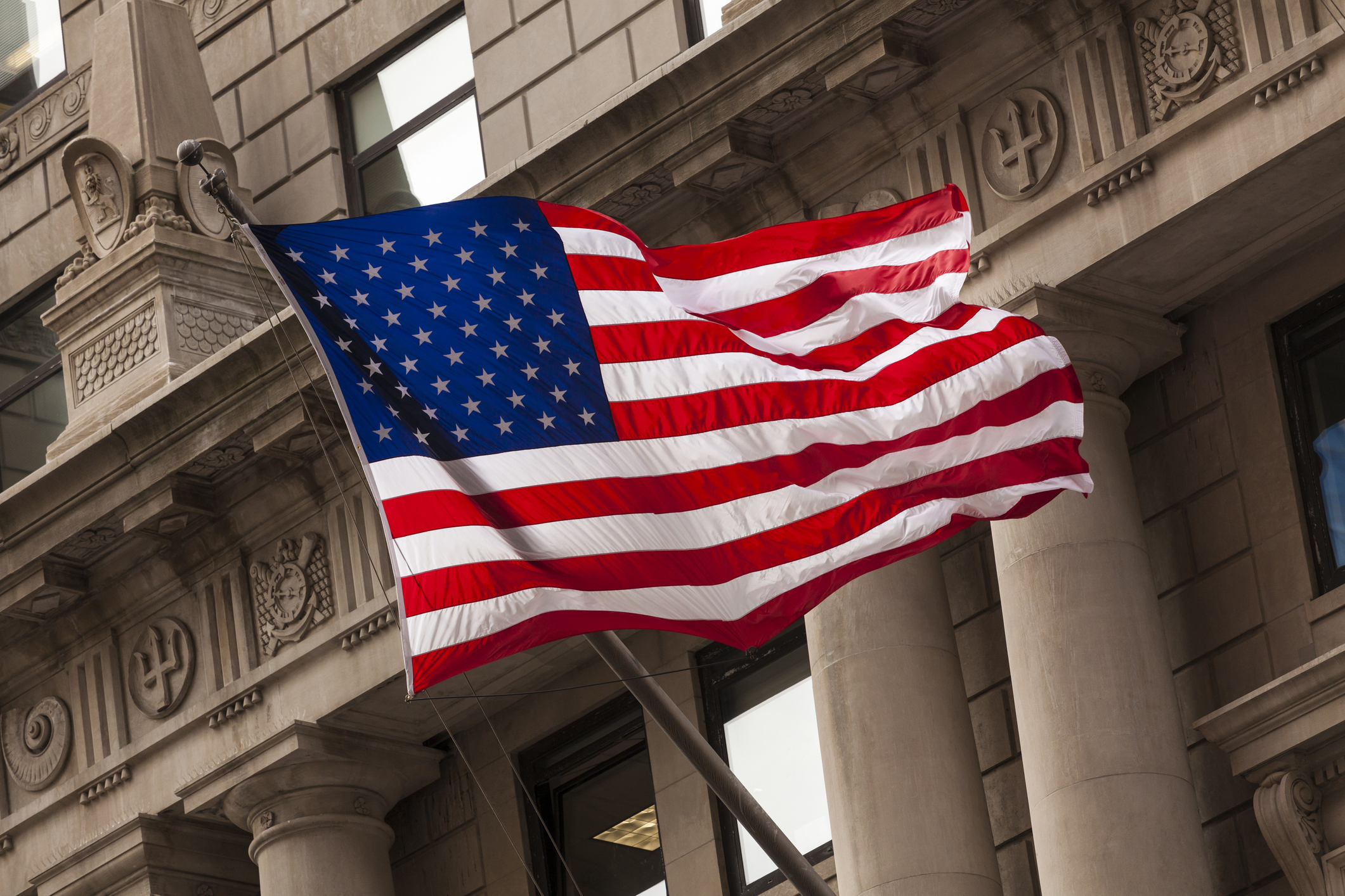 A flag flies in front of a building in New York City’s financial district.